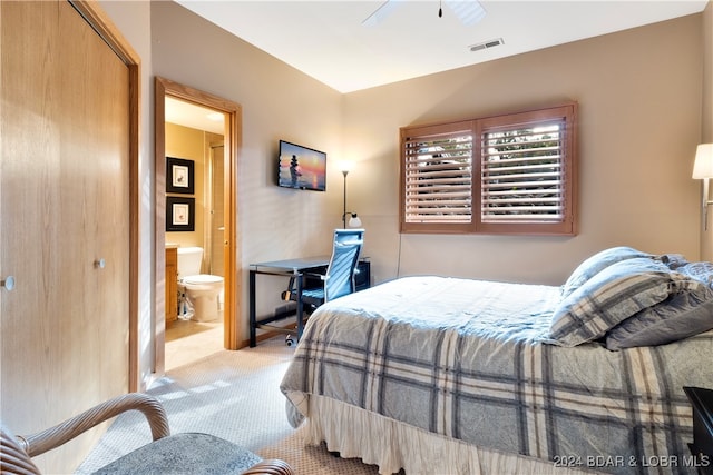 bedroom with ceiling fan, ensuite bathroom, and light carpet