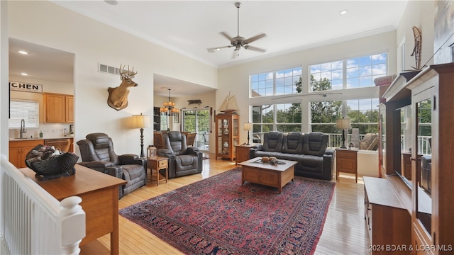 living room with ornamental molding, ceiling fan with notable chandelier, light hardwood / wood-style floors, and sink