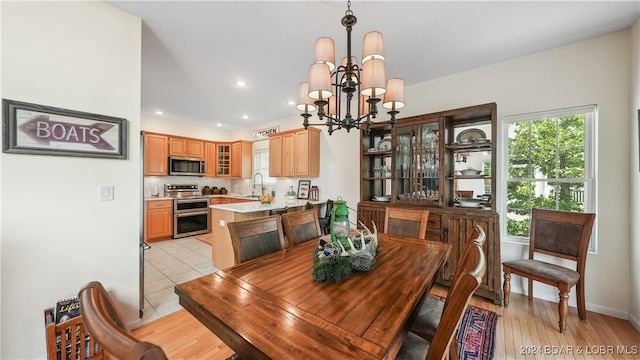 dining room with sink, a notable chandelier, and light hardwood / wood-style flooring