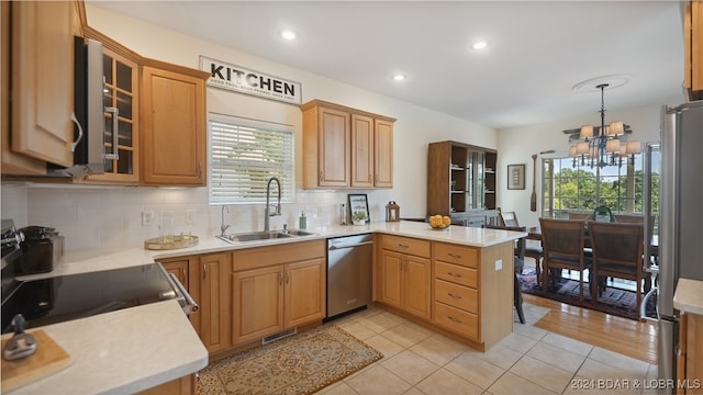 kitchen featuring kitchen peninsula, a chandelier, a healthy amount of sunlight, and appliances with stainless steel finishes