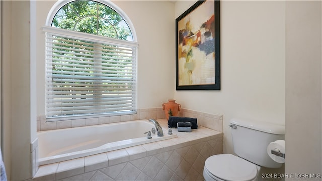 bathroom with toilet and tiled tub