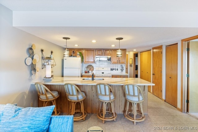 kitchen featuring white appliances, decorative backsplash, decorative light fixtures, light tile patterned flooring, and kitchen peninsula