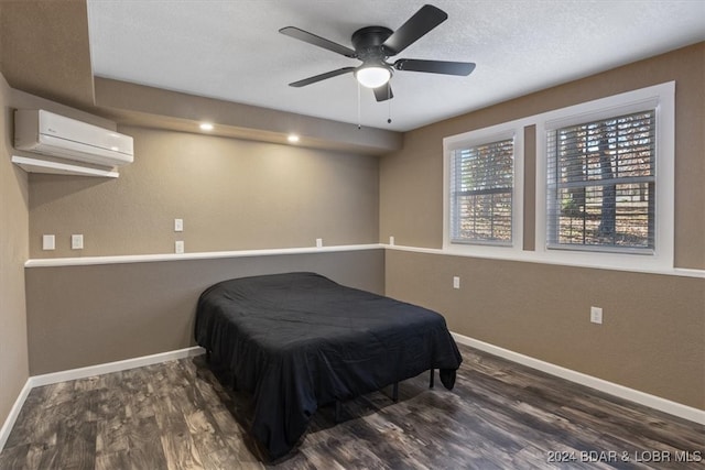 bedroom featuring a wall mounted AC, dark hardwood / wood-style floors, and ceiling fan