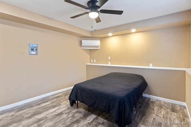 bedroom with wood-type flooring, a wall unit AC, and ceiling fan