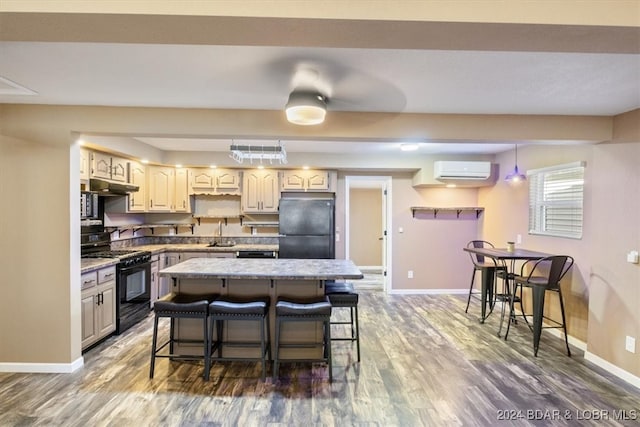 kitchen with light stone countertops, a kitchen breakfast bar, a wall mounted AC, black appliances, and dark hardwood / wood-style floors