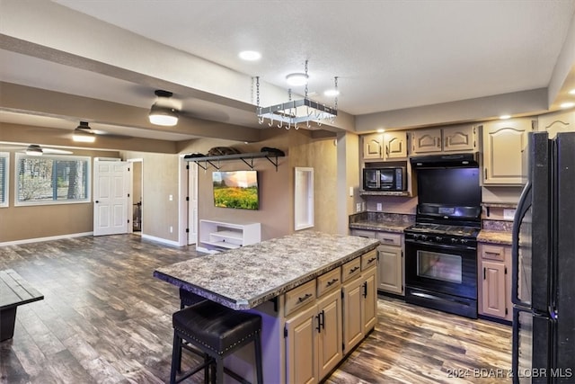 kitchen featuring a kitchen breakfast bar, dark hardwood / wood-style flooring, a center island, and black appliances