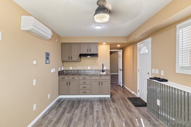 kitchen featuring a wall mounted air conditioner, hardwood / wood-style floors, gray cabinetry, and sink