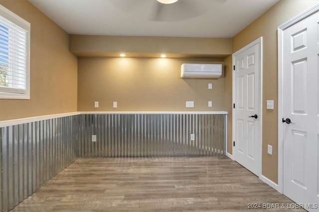 empty room with light hardwood / wood-style flooring and an AC wall unit