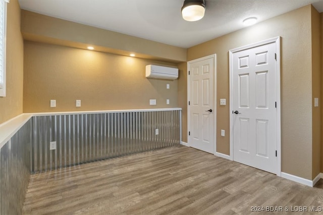 spare room featuring a wall mounted AC and hardwood / wood-style flooring