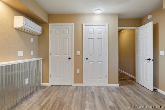 interior space featuring light wood-type flooring and an AC wall unit