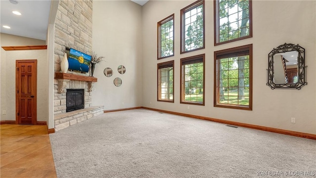 unfurnished living room with high vaulted ceiling, plenty of natural light, and a stone fireplace