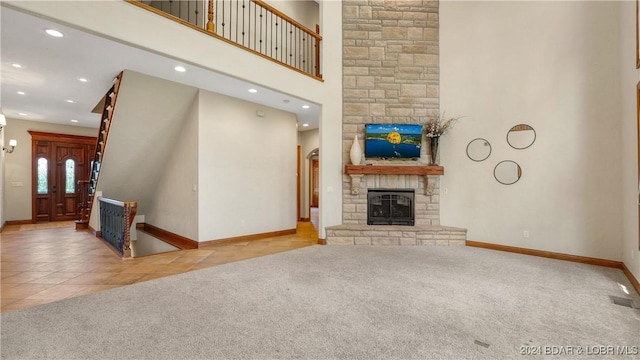 unfurnished living room with a fireplace, a high ceiling, and light colored carpet