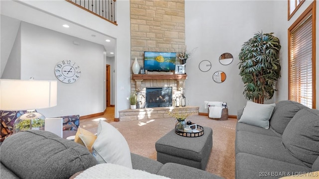 carpeted living room with a stone fireplace and a high ceiling