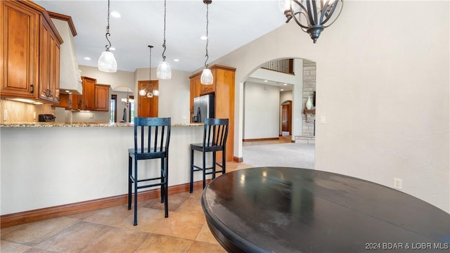 kitchen featuring a breakfast bar, a notable chandelier, decorative light fixtures, stainless steel fridge with ice dispenser, and kitchen peninsula