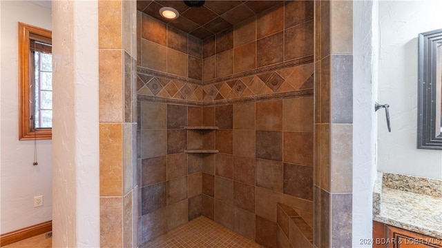 bathroom featuring tiled shower and vanity