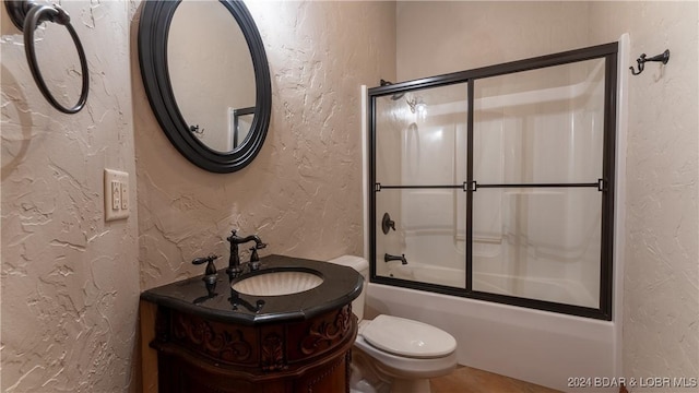 full bathroom featuring toilet, combined bath / shower with glass door, and vanity