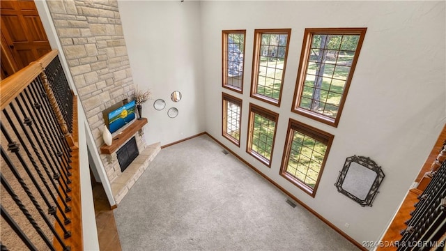 living room with a high ceiling, light colored carpet, and a fireplace