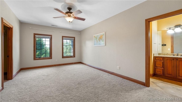 unfurnished bedroom featuring connected bathroom, ceiling fan, sink, and light colored carpet