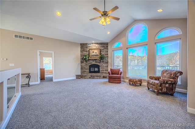 living room with carpet, high vaulted ceiling, ceiling fan, and a stone fireplace