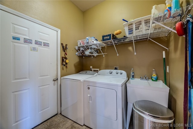 clothes washing area with washer and dryer, light tile patterned floors, and sink