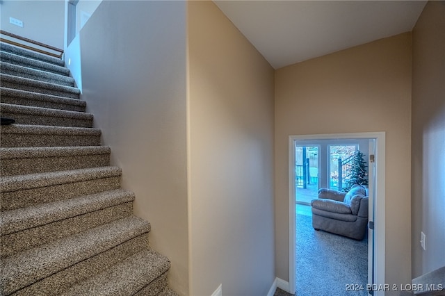 stairway featuring carpet floors and high vaulted ceiling