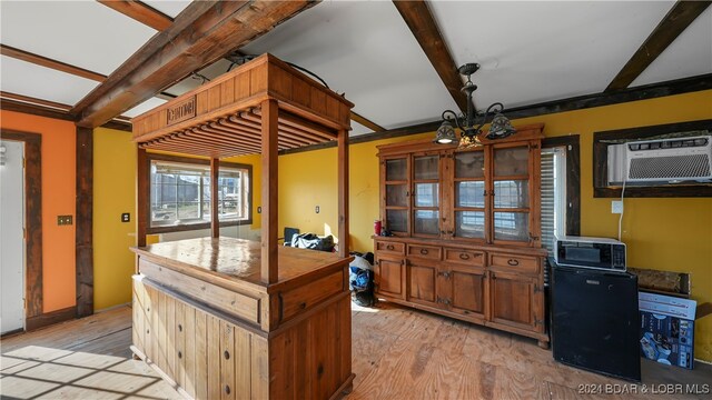 kitchen featuring an AC wall unit, beamed ceiling, light hardwood / wood-style floors, and a notable chandelier