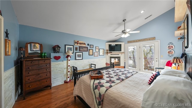 bedroom featuring ceiling fan, wood-type flooring, vaulted ceiling, access to outside, and tile walls