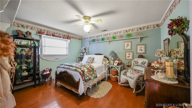 bedroom with ceiling fan, wood-type flooring, a textured ceiling, and ornamental molding