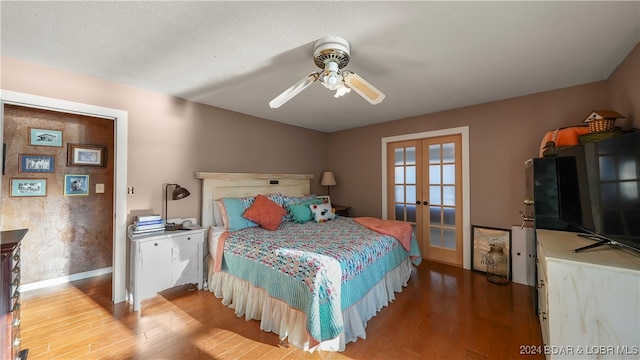 bedroom featuring ceiling fan, french doors, hardwood / wood-style floors, and a textured ceiling