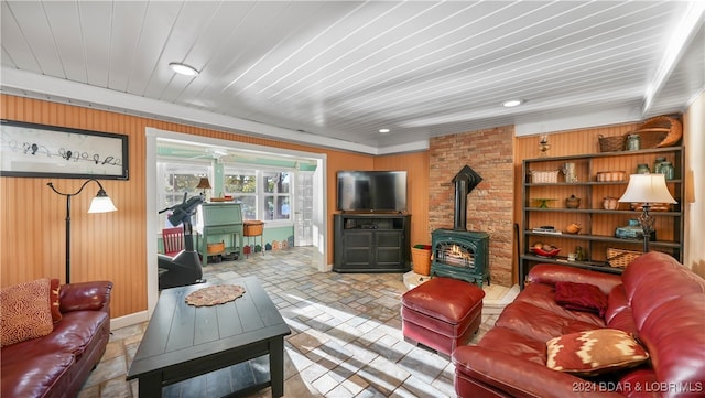 living room featuring a wood stove, wooden walls, and wooden ceiling