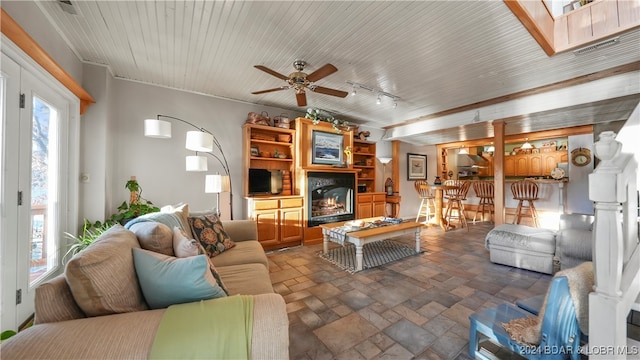 living room featuring ceiling fan, ornamental molding, and a skylight