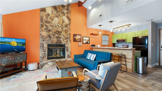 living room with a fireplace, light wood-type flooring, high vaulted ceiling, and beamed ceiling