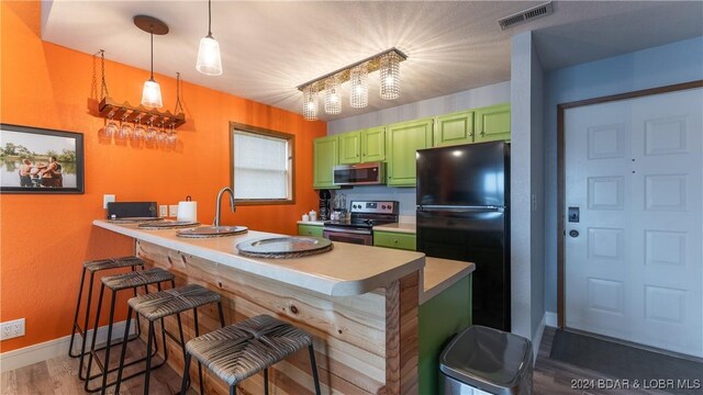 2500 Bay Point Ln Unit 645, Osage Beach, MO 65065 - kitchen with green cabinets, appliances with stainless steel finishes, a kitchen bar, and a peninsula
