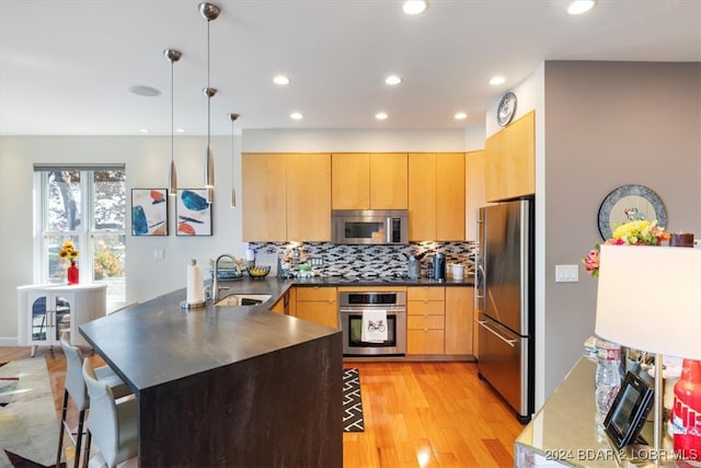 kitchen featuring pendant lighting, light brown cabinets, sink, and appliances with stainless steel finishes