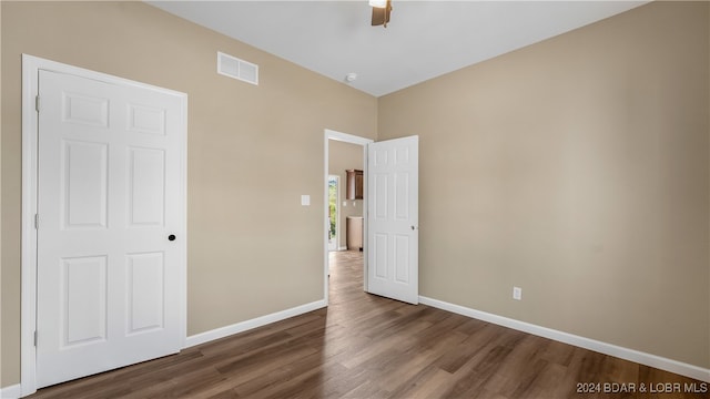 unfurnished bedroom with ceiling fan, dark hardwood / wood-style flooring, and a closet