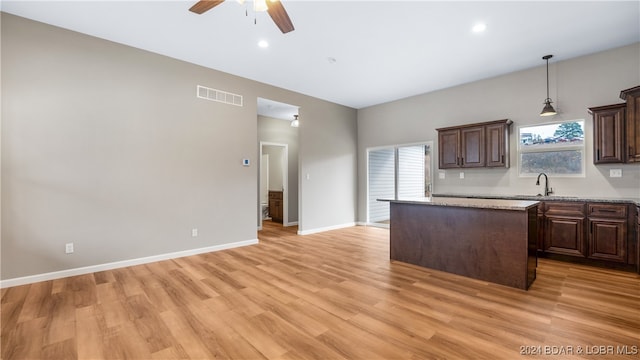 kitchen featuring a center island, light stone countertops, light hardwood / wood-style floors, and sink