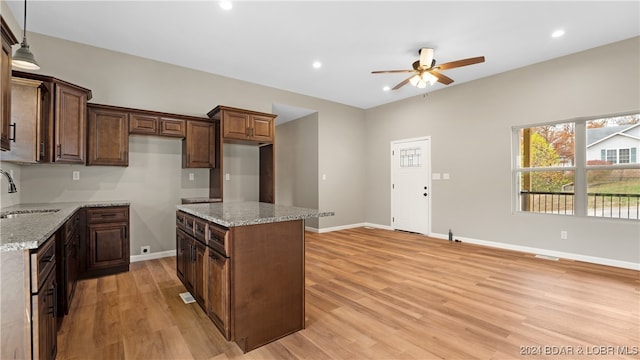 kitchen with a center island, light stone countertops, sink, and light hardwood / wood-style flooring