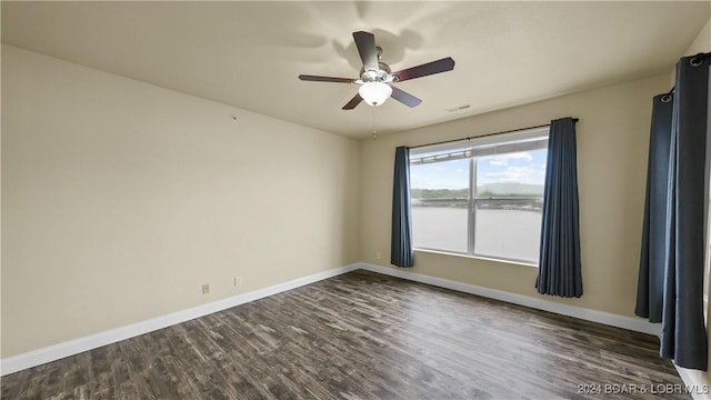 spare room featuring dark wood finished floors, visible vents, a ceiling fan, and baseboards