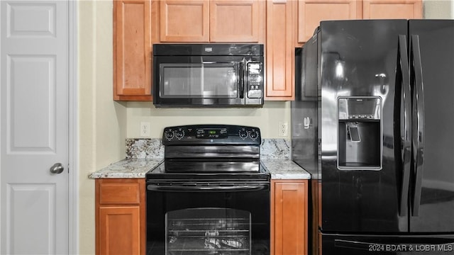 kitchen with light stone counters, black appliances, and brown cabinetry