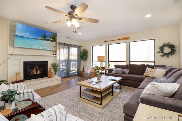 living room with hardwood / wood-style floors, ceiling fan, and a large fireplace