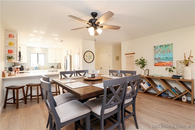 dining space with light hardwood / wood-style floors, ceiling fan, and sink