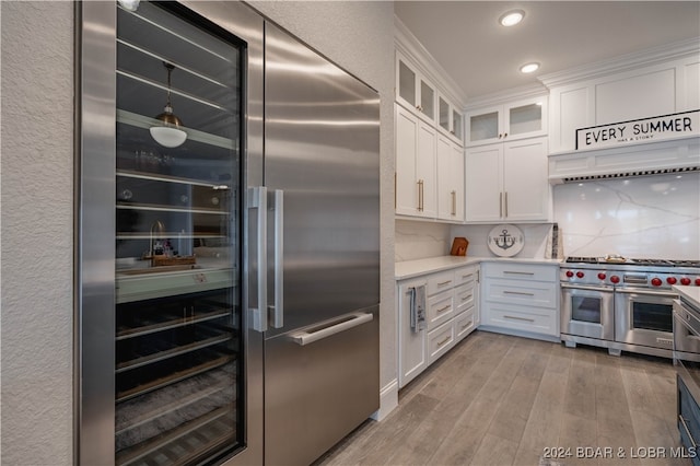 kitchen with light hardwood / wood-style flooring, white cabinetry, tasteful backsplash, and high quality appliances