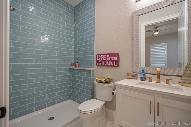 bathroom with a tile shower, ceiling fan, vanity, and toilet