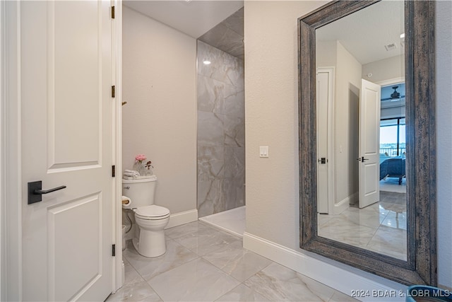 bathroom featuring tiled shower and toilet