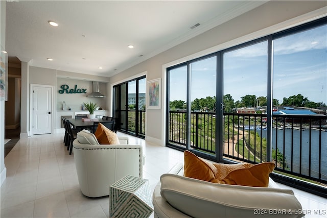 tiled living room with crown molding, plenty of natural light, a water view, and sink