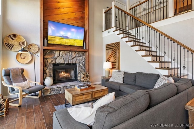 living room with a fireplace, dark wood-type flooring, and a high ceiling