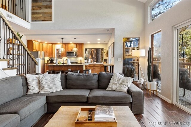 living room with a towering ceiling, dark wood-type flooring, and sink