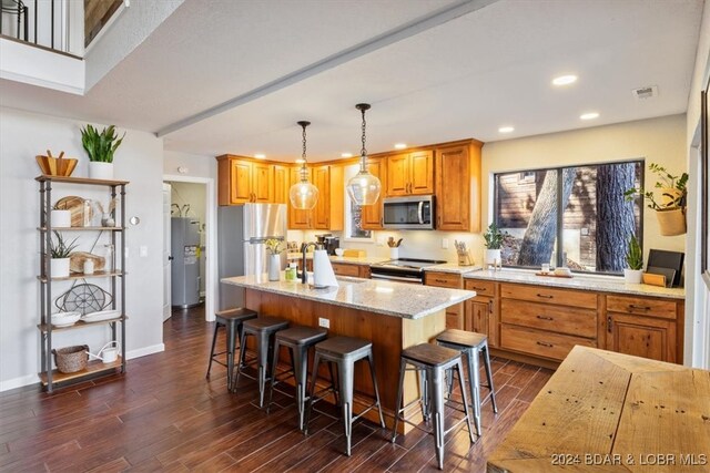 kitchen featuring light stone countertops, appliances with stainless steel finishes, dark wood-type flooring, decorative light fixtures, and a center island