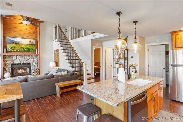 kitchen featuring sink, stainless steel appliances, dark wood-type flooring, an island with sink, and a breakfast bar