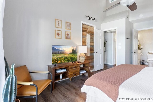 bedroom featuring a towering ceiling, ensuite bath, ceiling fan, and dark wood-type flooring